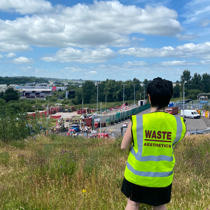 Artist wearing hi vis oversees recycling at remediated landfill site