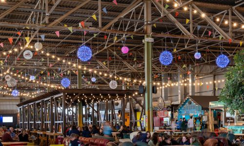 Inside image of the Marina Market in Cork with colourful lights handing from the roof