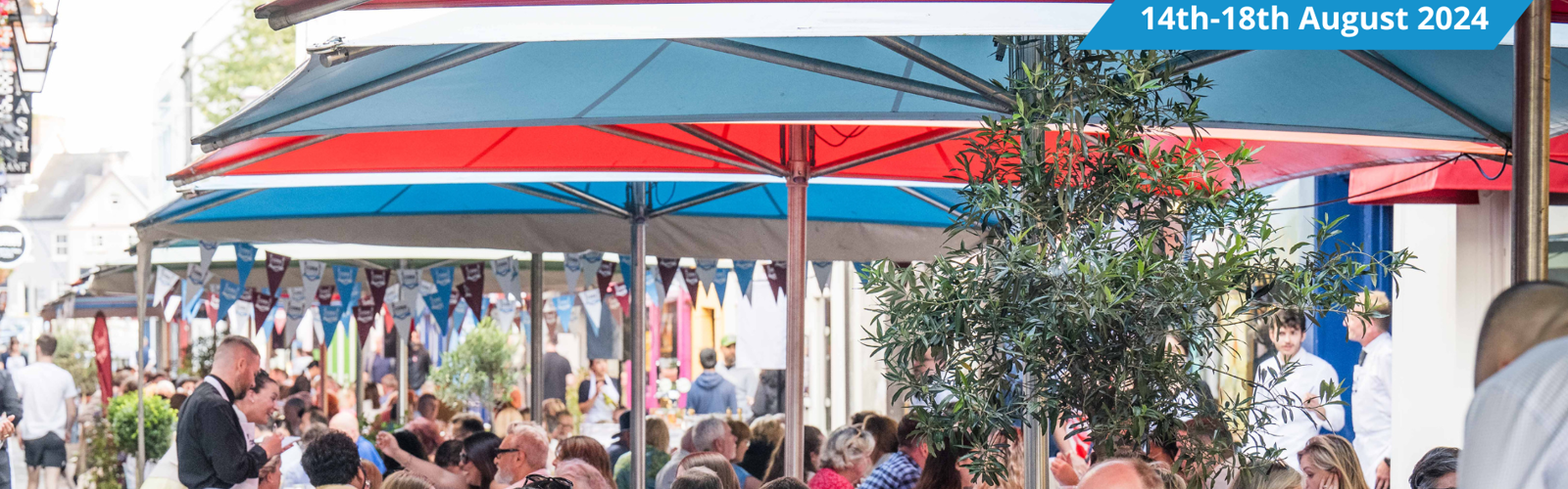 People dining on the street under blue and red umbrellas