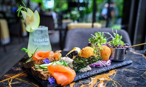 Platter of salmon and brown bread on a black slate with a rebel city drink lovely vibrant colours