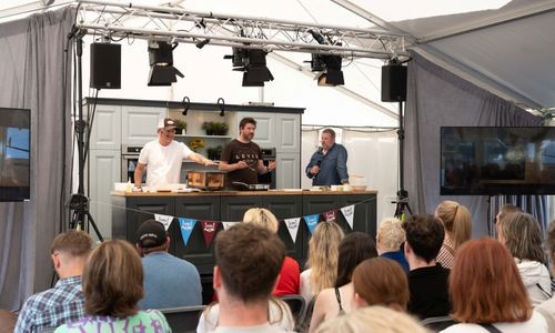 People on stage at cooking demo in marquee