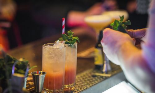 Pictures of two cocktails on a bar being prepared