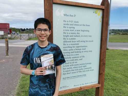 Student stands by display board showing the poem they had published in the Unfinished Book of Poetry